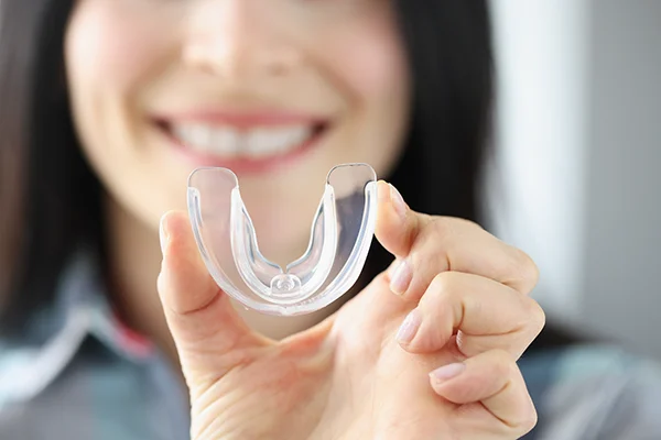 Close up of a simple mouthguard being held up by an excited white woman.